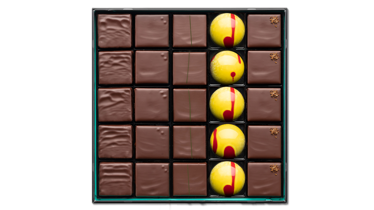 Assortiment de 25 chocolats artisanaux aux cinq saveurs : praliné amande-noisette, ganache nature, ganache citron vert, demi-sphère à la ganache miel et pâte d’amande au gingembre associée à une ganache à la baie de Sichuan. Patrick Roger